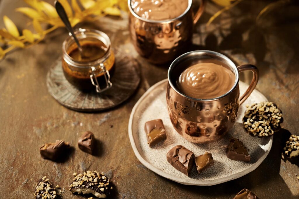 Vroča čokolada Chocomar v bakreni skodelici, obkrožena s koščki čokolade
